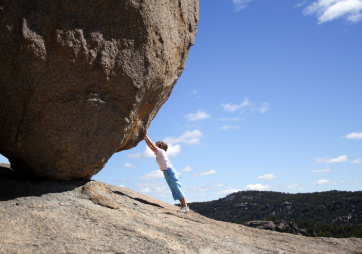 person holding up a large boulder from underneath